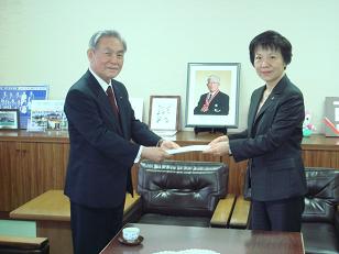 写真:多摩市指定企業指定通知書をJUKI株式会社に手渡す多摩市長(指定企業第21-1号)