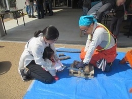 イベントで枝を切る親子とボランティアの写真