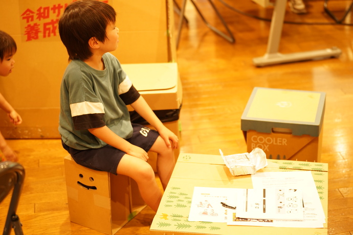 ダンボールの椅子に座っている男の子