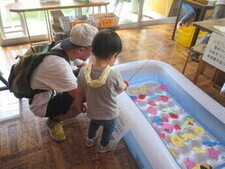 魚釣りゲームをする親子の写真