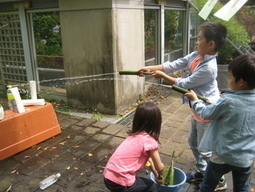 竹の水鉄砲で遊ぶ子どもの写真